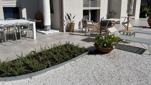 An outdoor patio area with a dining table and chairs, a potted plant, and a seating area with a sunshade. - MODERN DESIGN VILLA OVERLOOKING THE GULF OF MARINA DI CAMPO (Campo nell'Elba)