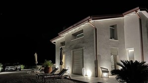 A modern house with a driveway, lounge chairs, and potted plants. - MODERN DESIGN VILLA OVERLOOKING THE GULF OF MARINA DI CAMPO (Campo nell'Elba)