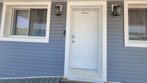A house with a white front door labeled "Superior," a window with a curtain, and a small porch area. - Modern Retreat on Lake Superior, close to the Snowmobile trails! (Baraga)