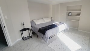 A bedroom with a bed, a bedside table, a shelf unit, and a desk. - Modern Retreat on Lake Superior, close to the Snowmobile trails! (Baraga)
