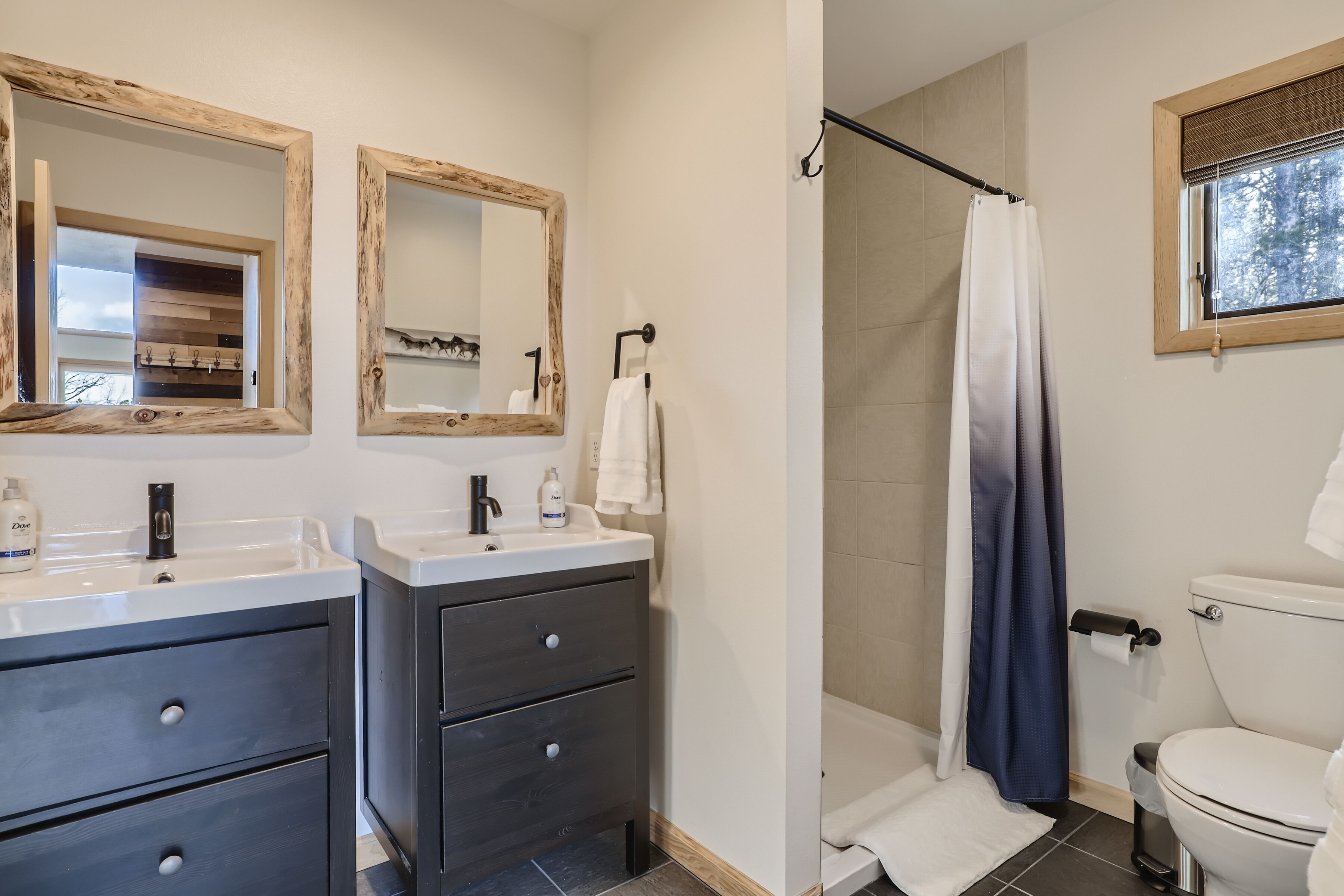 A modern bathroom with two sinks, a shower, and a toilet.