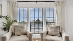A room with two beige armchairs, a small round table, and a potted plant.