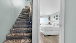 Una escalera de piedra conduce a un dormitorio con cama y mesita de noche.