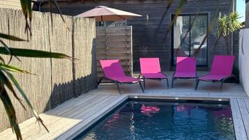 Relax by the pool surrounded by a wooden deck and lounge chairs.