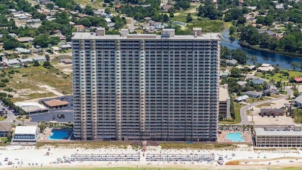 A high-rise hotel with multiple floors, a swimming pool, and a beach area. - Super clean, lower level, recently renovated and beachfront - walk to Pier Park (Panama City Beach)