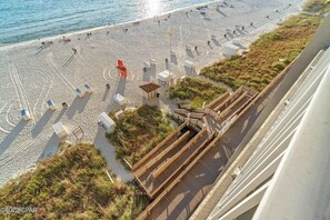 Una playa con tumbonas y un paseo marítimo de madera que lleva a una pequeña construcción.