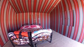 Cozy retreat with a single bed, striped wallpaper, and plush carpeting.