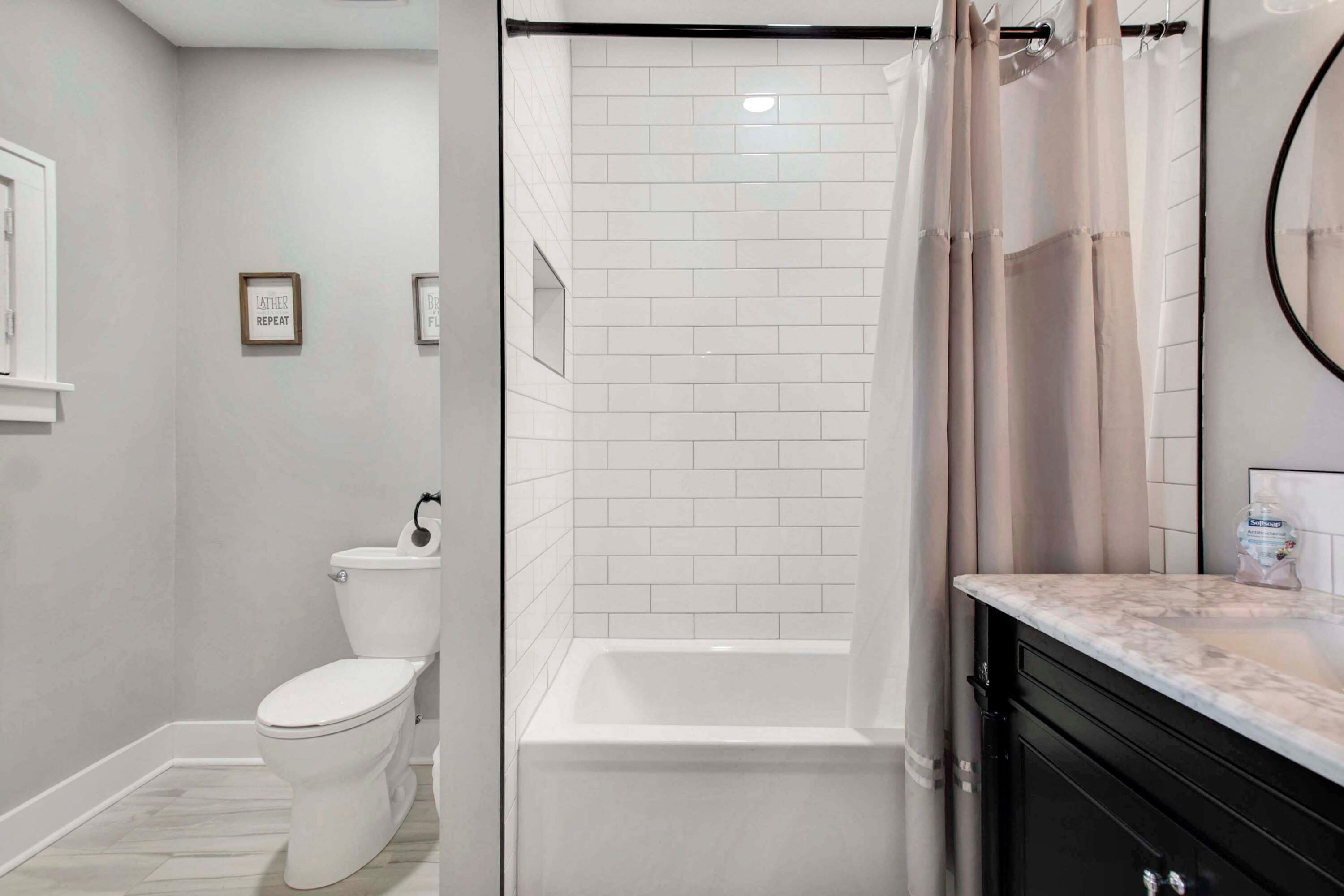 A bathroom with a toilet, shower, and a vanity with a mirror.