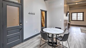 A room with a round table and four chairs, a staircase, and a window. - Cherokee Vacation Rental - On Main Street! (Cherokee)
