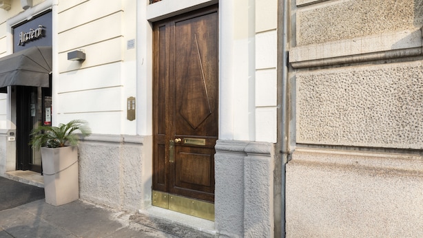 A building with a large wooden door, a potted plant, and a sign that reads "Ancient." - notaMI - BICOCCA Home - 2 Bedrooms (Milan)