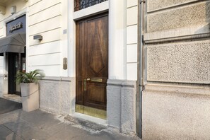 A building with a large wooden door, a potted plant, and a sign that reads "Ancient." - notaMI - BICOCCA Home - 2 Bedrooms (Milan)