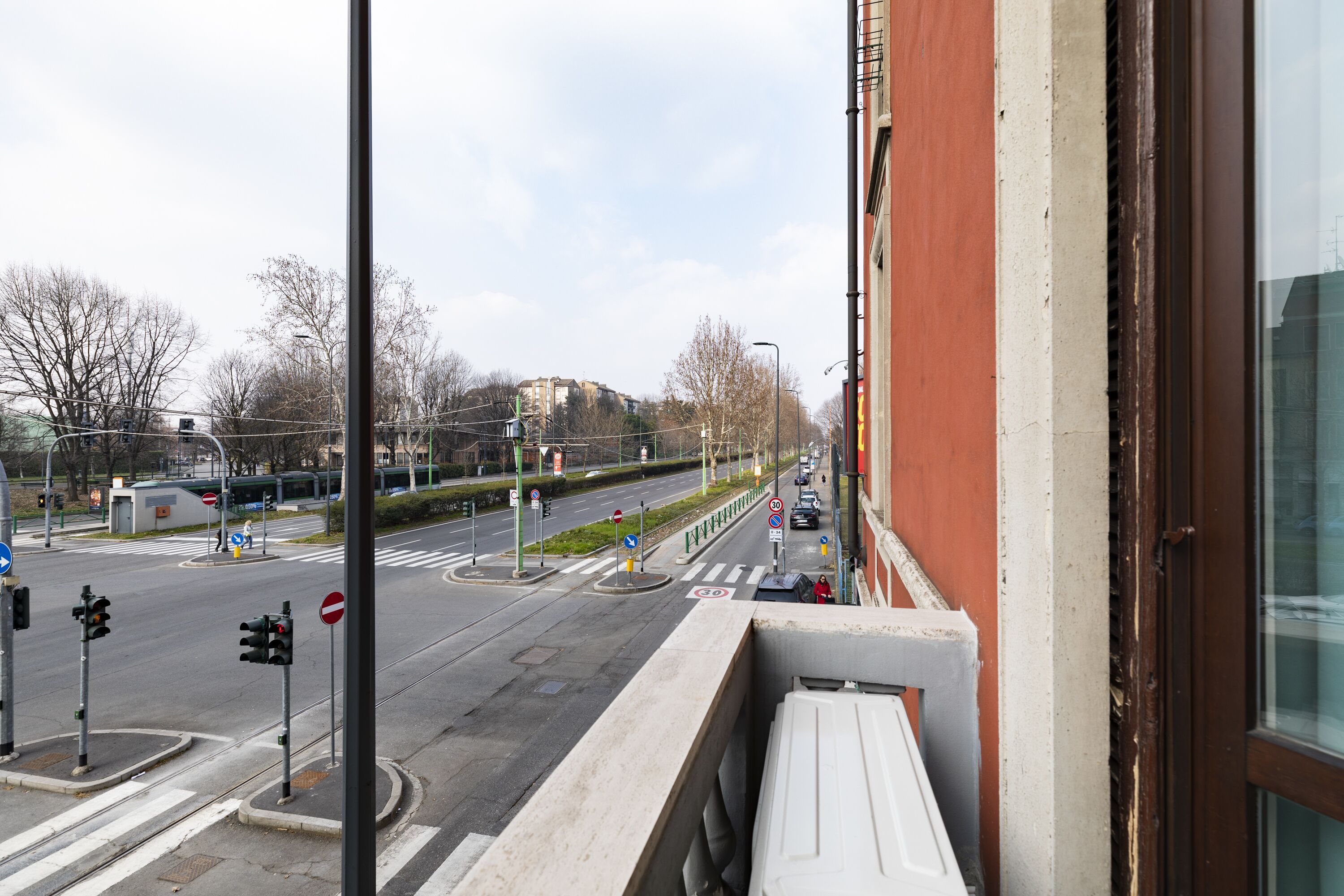 Une vue de rue avec des feux de signalisation, des panneaux de signalisation et un bâtiment à la façade rouge.