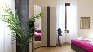 A modern hotel room with a bed, a potted plant, a mirror, and a view of another room. - notaMI - BICOCCA Home - 2 Bedrooms (Milan)
