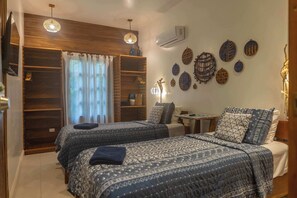 A bedroom with two beds, a wardrobe, a window with curtains, and wall decorations.