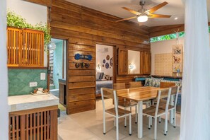 A wooden interior with a dining area, a ceiling fan, and a kitchen visible through an open door.