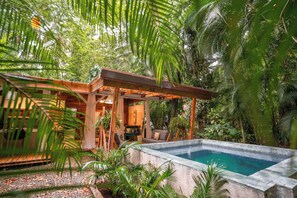 A wooden structure with a pool, surrounded by lush greenery.