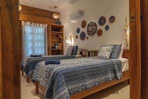 Une chambre avec deux lits, une armoire en bois, un bureau et des œuvres d’art décoratives accrochées au mur.