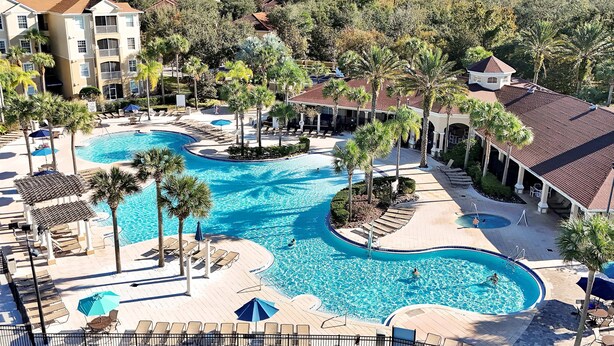 Et resort med flere swimmingpools, palmer og udsigt over det omkringliggende landskab.