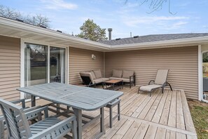 A covered patio with a table and chairs, a sliding glass door, and a small seating area with cushions.