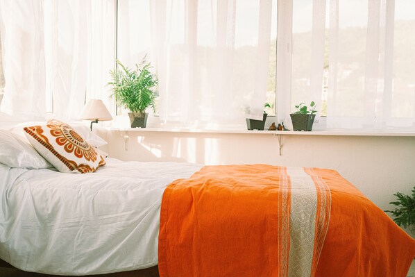 A bedroom with a bed, a window with sheer curtains, and potted plants on the windowsill. - DT Puerto Vallarta - Bright Apt w/ Breathtaking Views - Mins to Beach (Puerto Vallarta)