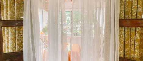 Una habitación con puerta de madera y ventanas con cortinas estampadas.