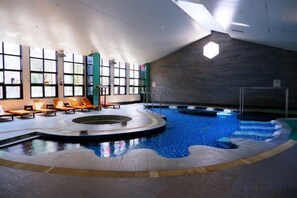 Une piscine intérieure avec un espace baigné de lumière et des chaises longues.