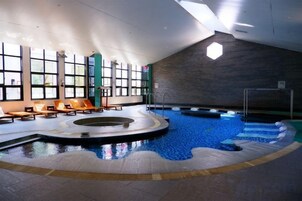 Una piscina interior con una zona soleada y sillones de descanso.