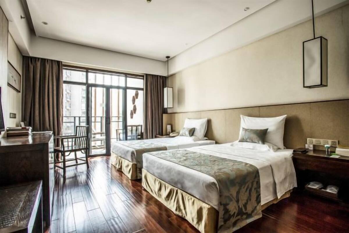 Een hotelkamer met twee bedden, een bureau, een stoel en een groot raam.