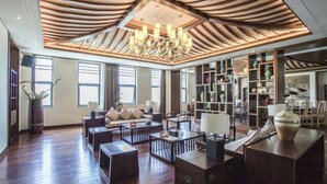 Un vaste espace de vie doté d’un plafond en bois, d’un lustre et d’une bibliothèque remplie d’objets décoratifs.