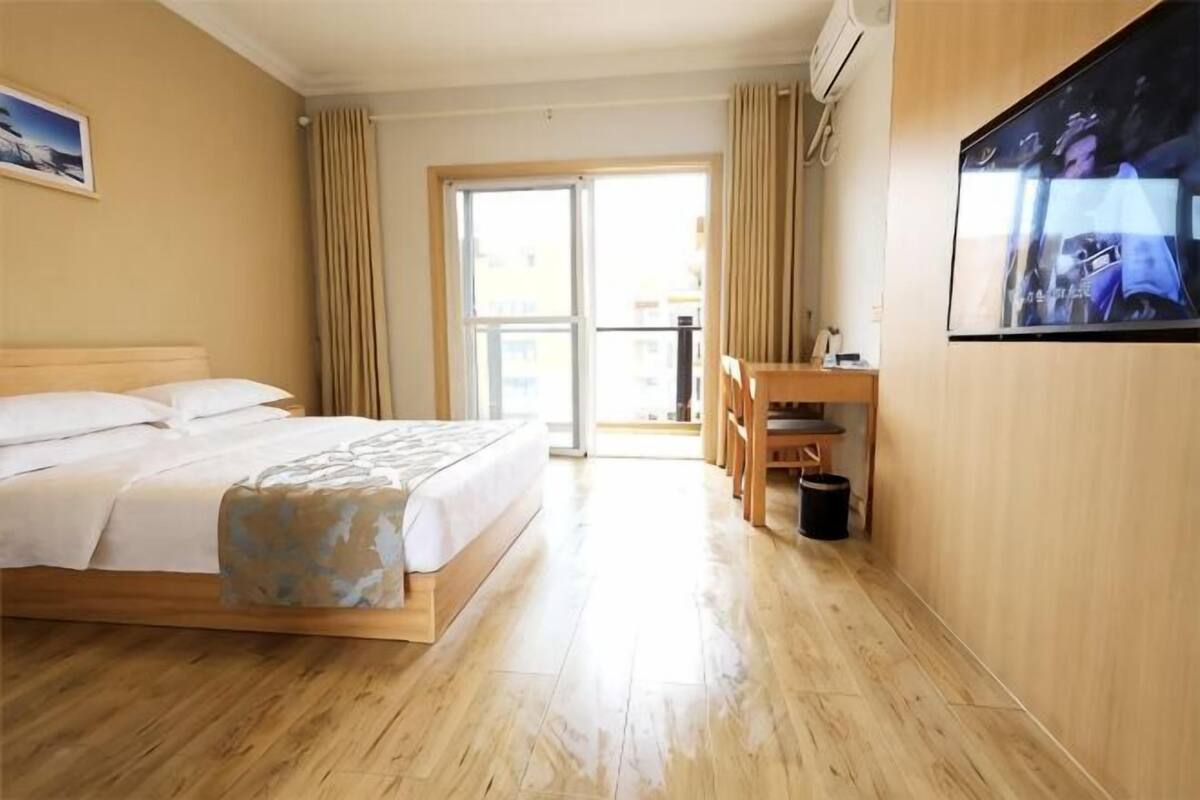 Een hotelkamer met een bed, een bureau, een stoel, een televisie en een balkon.