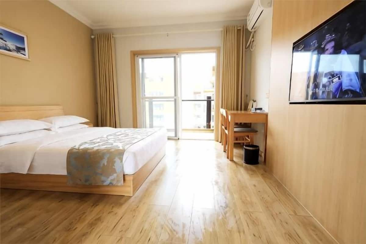 A hotel room with a bed, a desk, a chair, a TV, and a balcony.