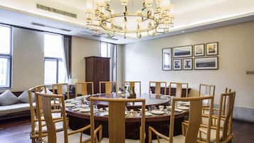Un comedor con una mesa redonda, sillas de madera, una araña y cuadros en la pared.