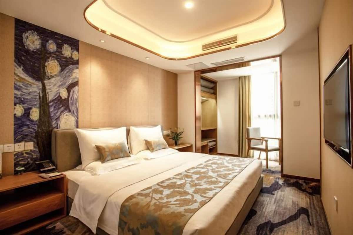 Een moderne hotelkamer met een groot bed, een schilderij aan de muur, een televisie en een inloopkast.