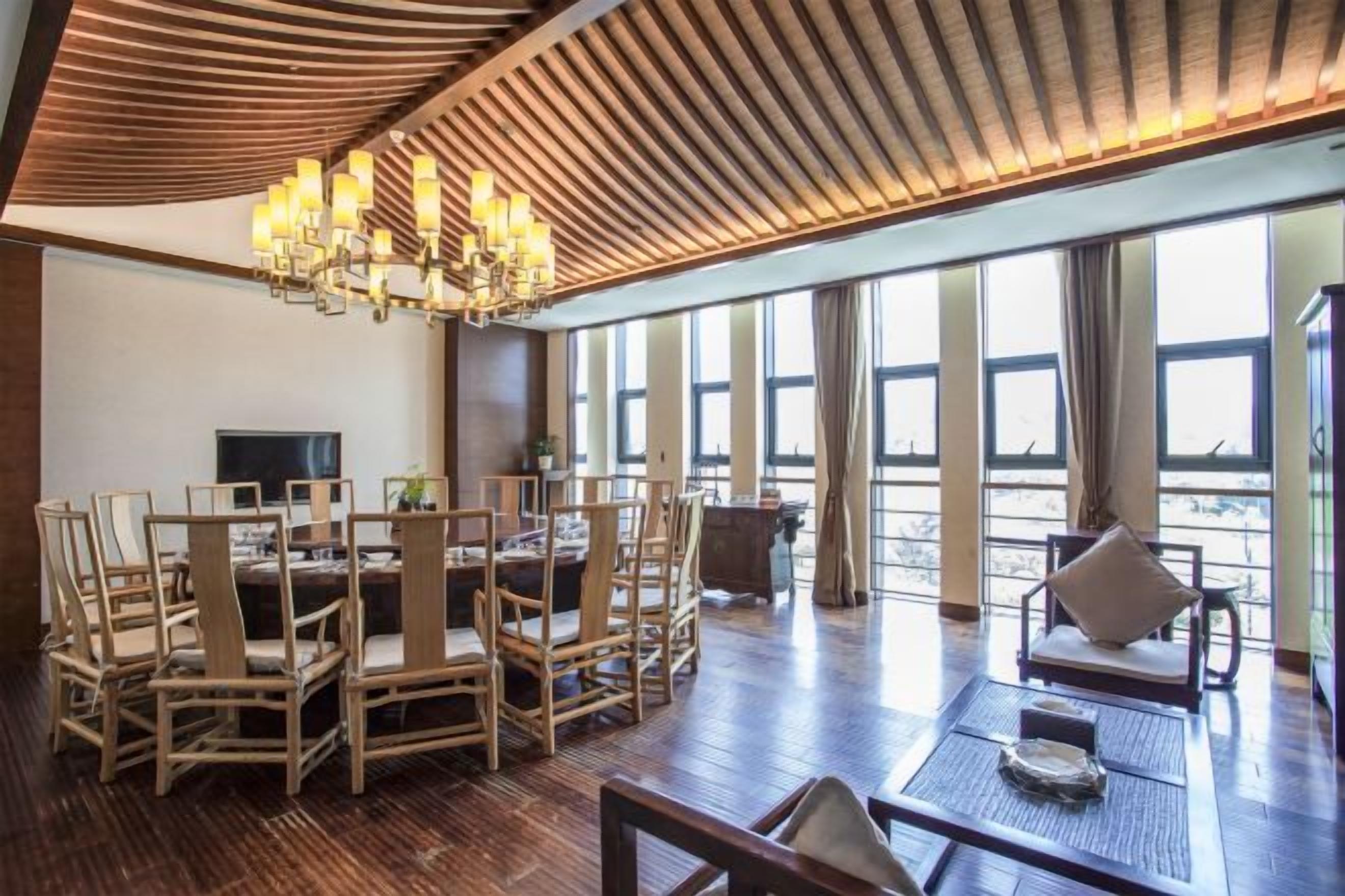 A spacious room with a large dining table, comfortable seating, a television, and large windows offering a view.