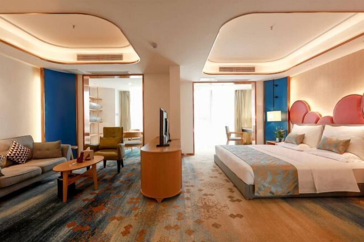Een hotelkamer met een bed, bank, fauteuil, televisie en een klein tafeltje.