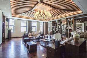 Un vaste espace de vie doté d’un haut plafond, de boiseries, d’un lustre et d’une grande bibliothèque.