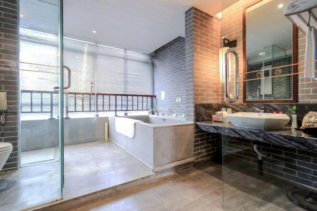Een moderne badkamer met een douchecabine van glas, een vrijstaand bad en een marmeren aanrechtblad met een wastafel.