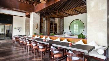 A long dining table with chairs, a bar area, and a large mirror on the wall.
