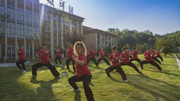 A group of people in red shirts performing an exercise routine outdoors.
