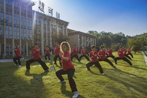 Un groupe de personnes portant des t-shirts rouges effectue une série d'exercices à l'extérieur.