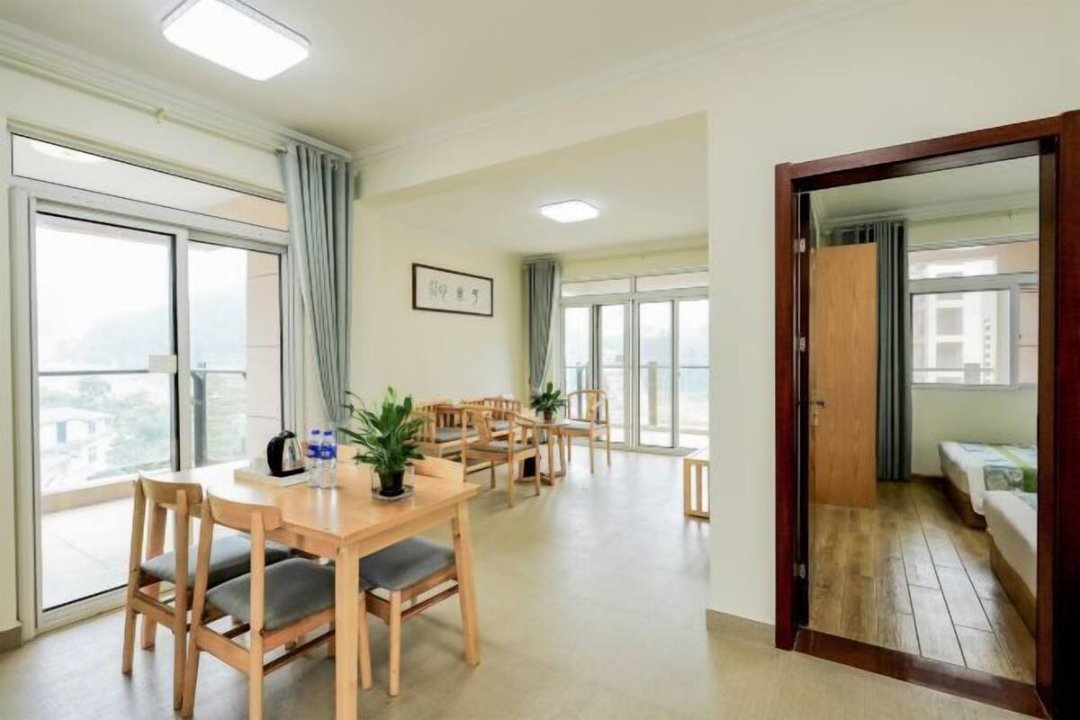 Een ruime kamer met een grote eettafel, meerdere stoelen en uitzicht door grote ramen.