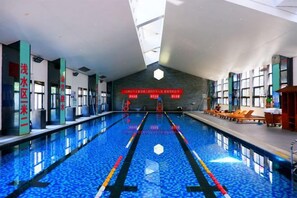 Una piscina interior con carriles claramente delimitados, suelo de baldosas y un techo alto con tragaluces.
