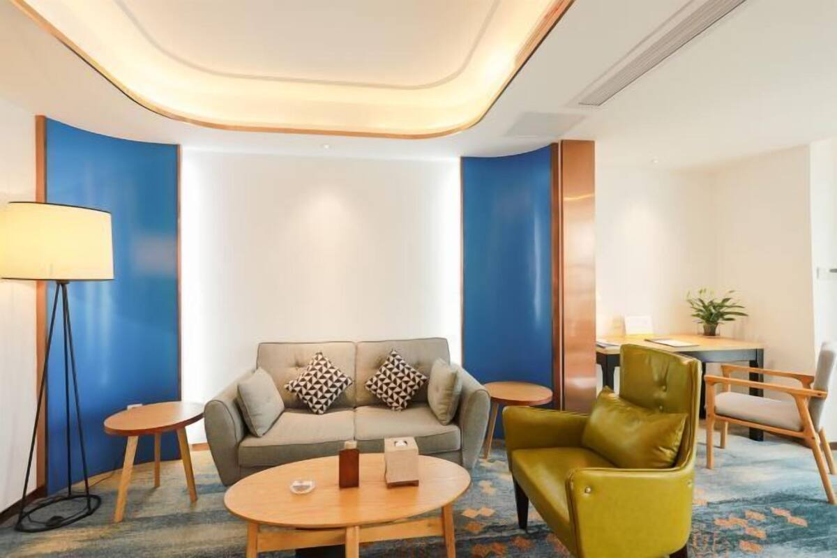 Een moderne hotel lobby met een bank, een ronde tafel, een lamp en een klein eetgedeelte.