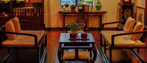 A traditional room with wooden furniture, a central table, and a window with decorative items.