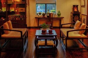 A traditional room with wooden furniture, a central table, and a window with decorative items. - Oriental Tianyuewan Hot Spring Hotel (Yuexi)