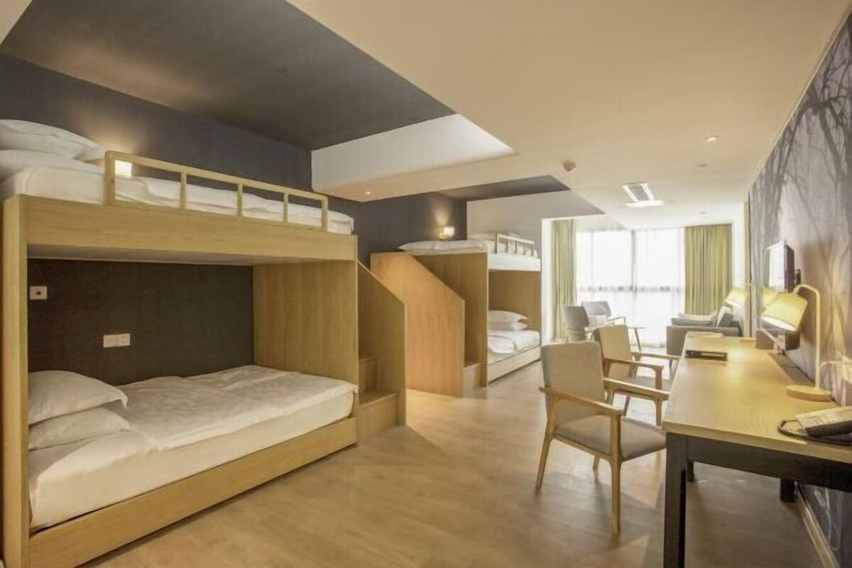 Une chambre d’hôtel avec des lits superposés, un bureau, une chaise et une grande fenêtre.
