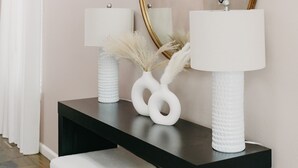 A modern bathroom with a black vanity, two white lamps, and a large mirror with a gold frame. - Spacious 3 BR House w/hot tub in SE Portland, Sleeps 8, near popular attractions (Wood Village)