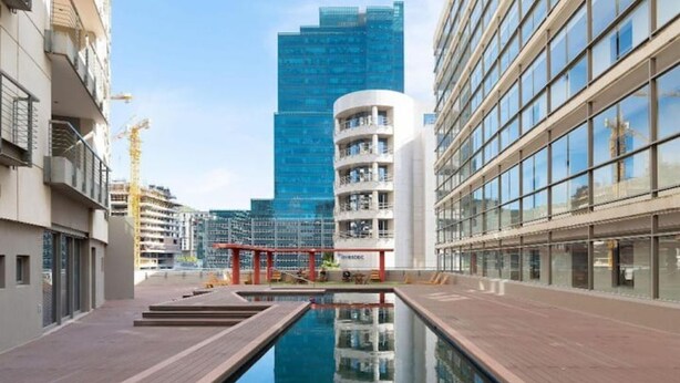 Een modern gebouw met een zwembad, glazen gevel en een kraan op de achtergrond.