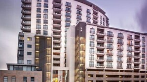 Een hotel met meerdere verdiepingen, een gebogen gevel, tal van balkons en een opvallende glazen ingang.