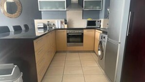 Een moderne keuken met een centraal eiland, een inbouwoven, een magnetron en een wasmachine.